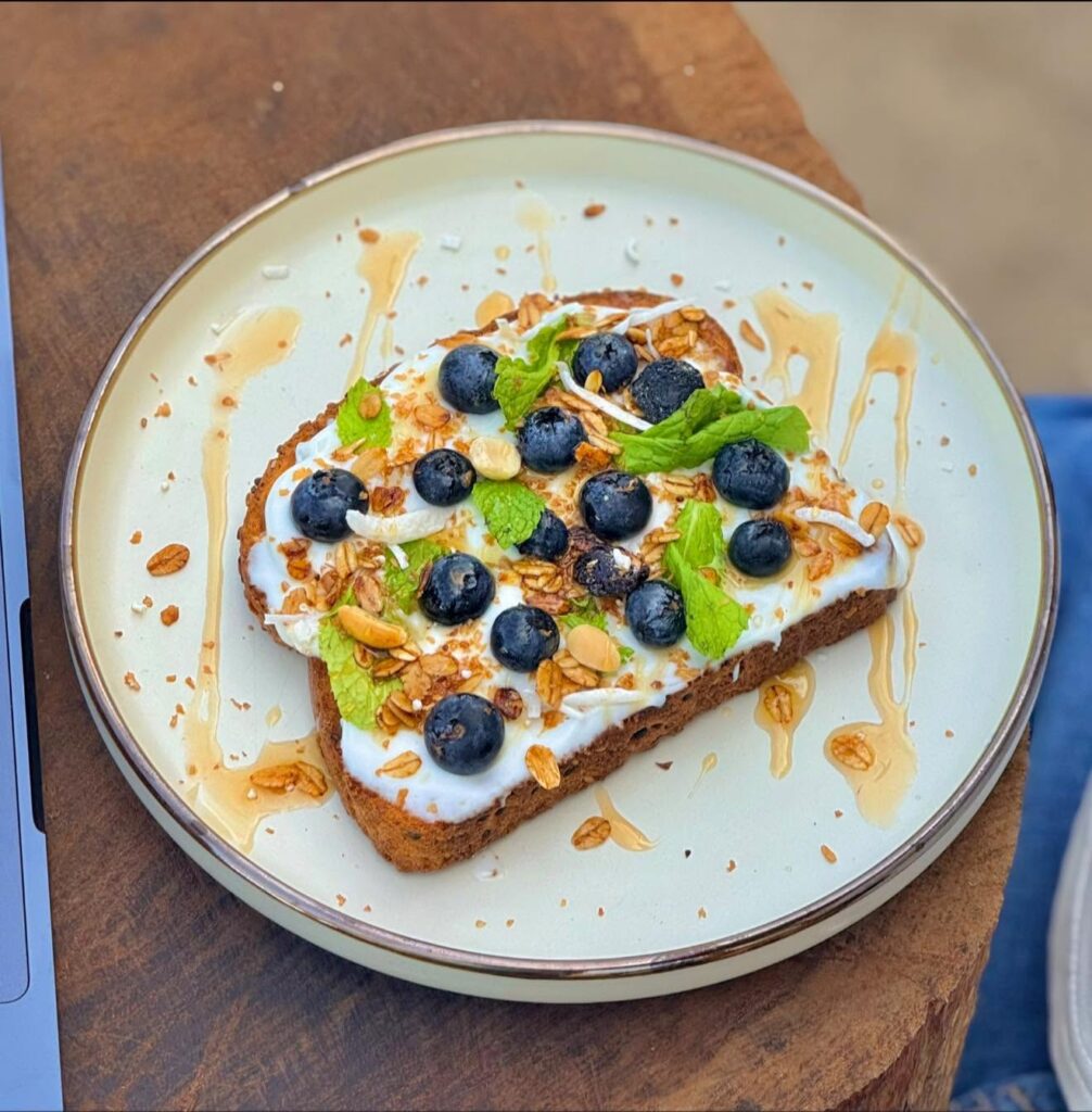 Mangle Blanco: pan tostado con yogurt, granola, moras azules, hojas de menta y un hilo de miel